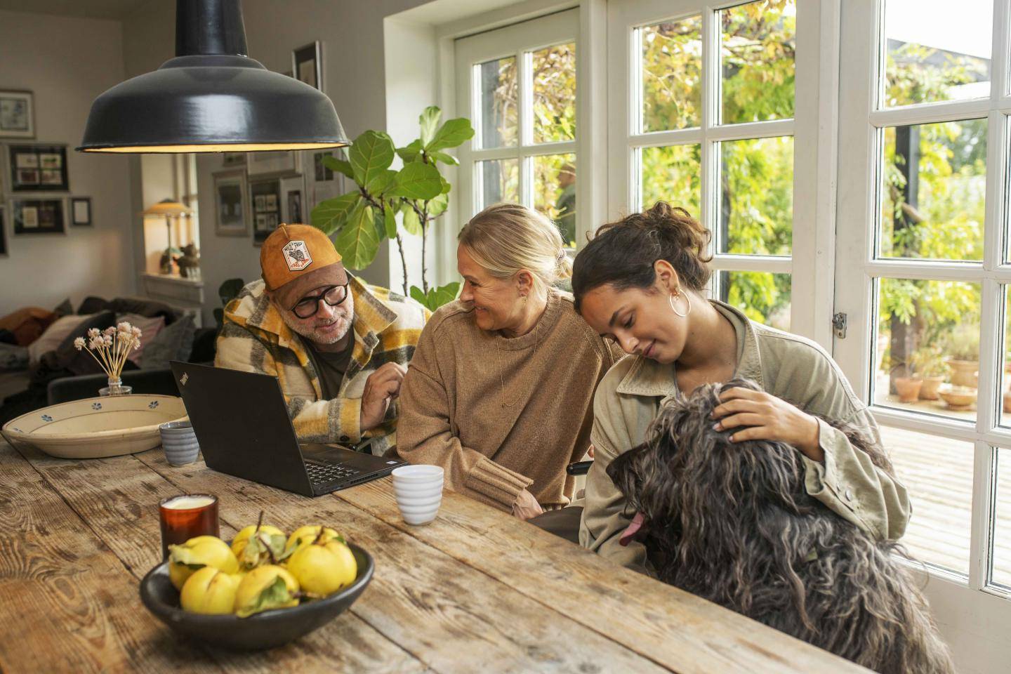 Familie med hund sidder ved spisebord, fotografi